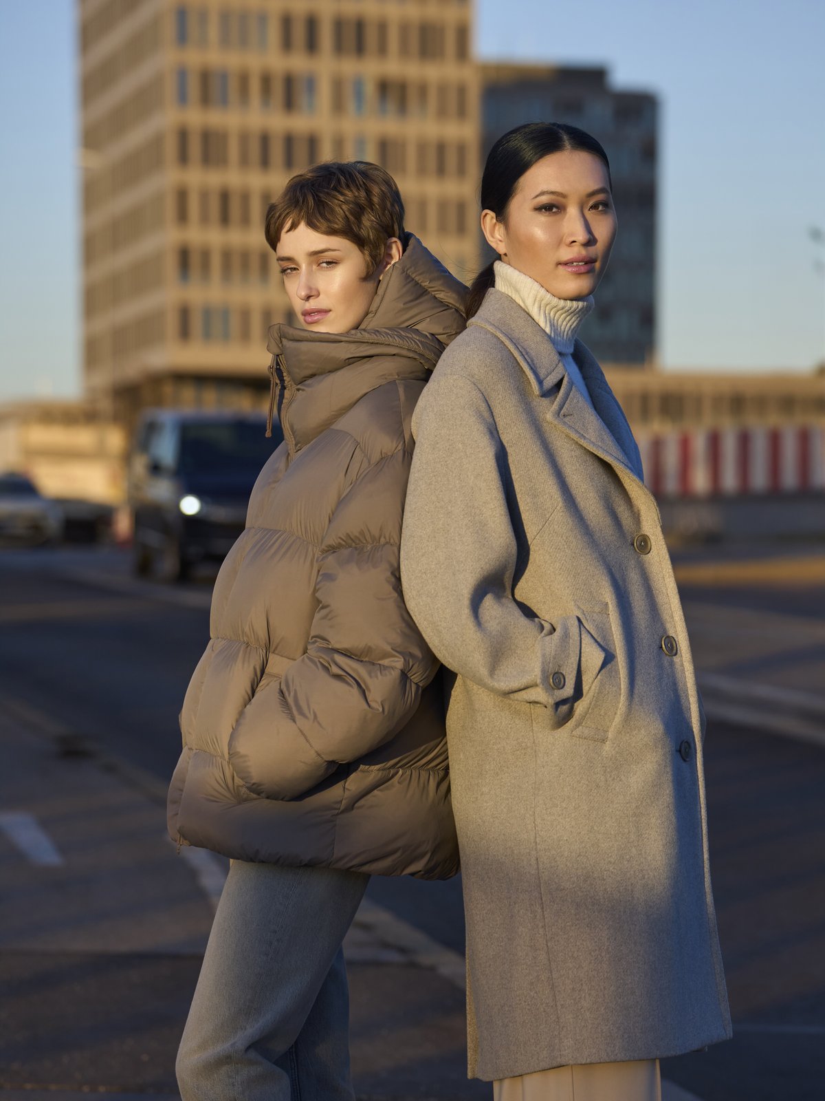 Two women in a city street in autumn light, one in a taupe puffer jacket and one in a light grey wool coat by LangerChen