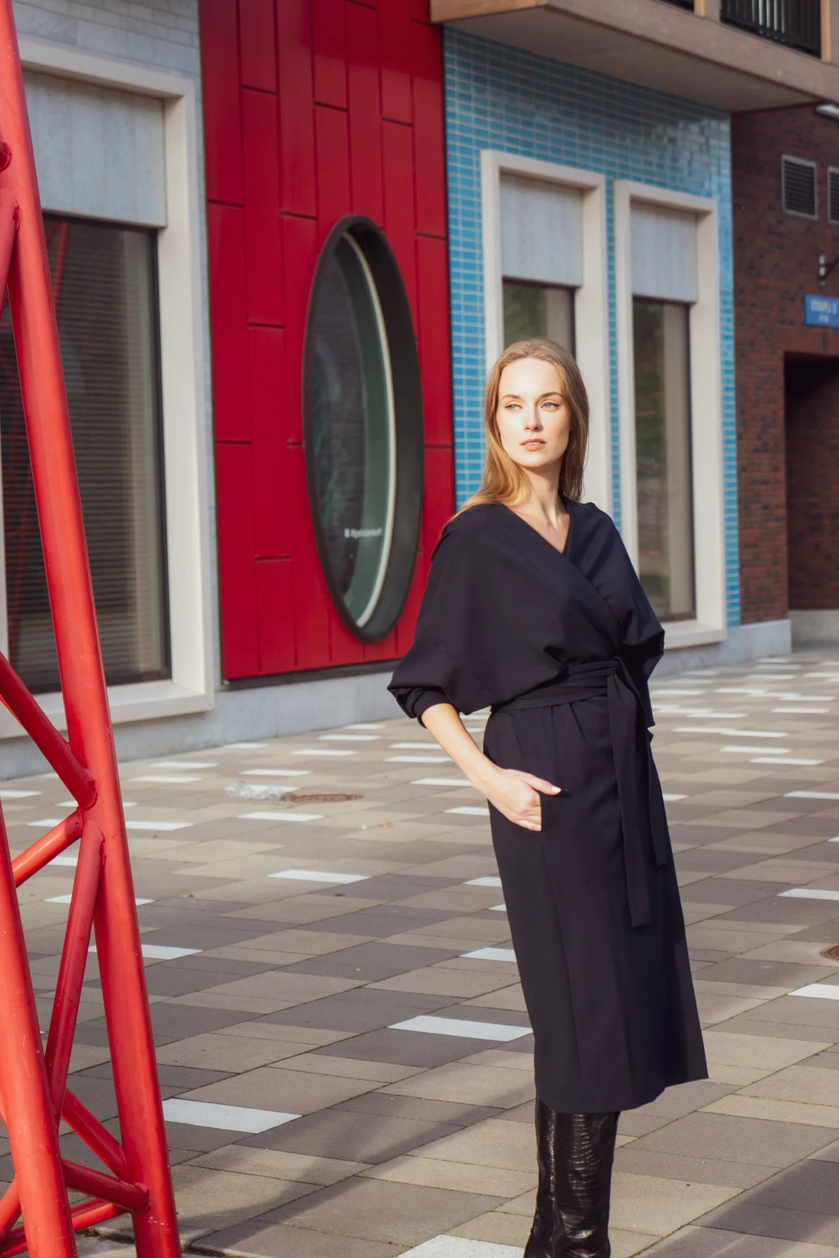 Woman in a black outfit standing in front of a red building